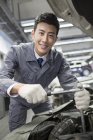 Mecánico auto chino trabajando en taller de reparación - foto de stock