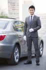 Chinese chauffeur standing next to car — Stock Photo