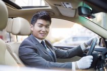 Chinese chauffeur sitting in car and smiling — Stock Photo