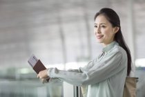 Зрелая китаянка ждет в аэропорту с билетом — стоковое фото