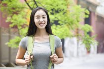 Китайська жінка з рюкзак, стоячи на вулиці і посміхається — стокове фото