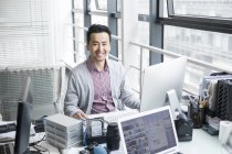 Chinese man sitting in office at computer desk — Stock Photo
