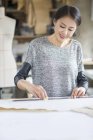 Diseñador de moda chino trabajando en atelier - foto de stock