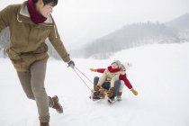 Chinese father pulling children on sled — Stock Photo