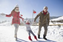 Des parents chinois tirant leur fille sur la neige — Photo de stock