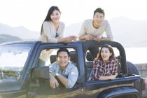 Amigos chineses sentados no carro e olhando na câmera — Fotografia de Stock