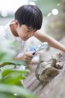 Chinese boy using magnifying glass in museum of natural history — Stock Photo