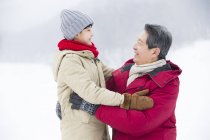 Chinese grandfather and grandson embracing on snow — Stock Photo