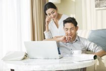 Jeune couple chinois utilisant un ordinateur portable à la maison — Photo de stock