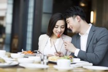 Chinese man feeding girlfriend in restaurant — Stock Photo