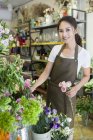 Chinesischer Ladenbesitzer hält Blumen in Blumenladen — Stockfoto