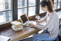 Studente cinese di sesso femminile che studia con il computer portatile in caffè — Foto stock