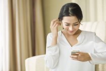 Donna cinese utilizzando smartphone a casa — Foto stock