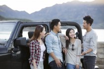 Chinese friends chatting in front of car in suburbs — Stock Photo