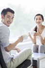 Casal chinês sentado com xícaras de café no café — Fotografia de Stock