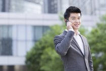 Chinese businessman talking on phone on street — Stock Photo