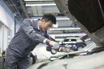 Mecânico de automóveis chinês trabalhando na oficina de reparação — Fotografia de Stock
