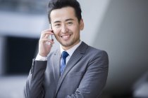 Китайский бизнесмен разговаривает по телефону и улыбается — стоковое фото