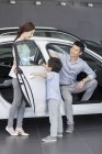 Chinese family sitting in new car in showroom — Stock Photo