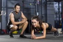 Chinese woman working out with trainer in gym — Stock Photo