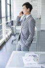 Homme d'affaires chinois parlant au téléphone au bureau — Photo de stock