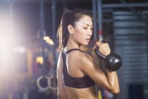 Chinese woman training with kettlebell in crossfit gym — Stock Photo
