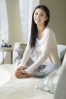 Donna cinese seduta sul divano in casa interna — Foto stock