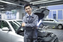 Chinesischer Automechaniker steht mit Taschenlampe in Werkstatt — Stockfoto