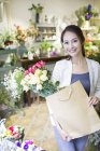 Китаянка, стоящая с цветочными букетами в магазине — стоковое фото