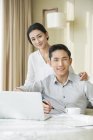 Joven pareja china utilizando el ordenador portátil en casa - foto de stock