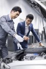 Chinese auto mechanic showing car engine to car owner — Stock Photo