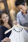 Casal chinês escolhendo vestido na loja de roupas — Fotografia de Stock