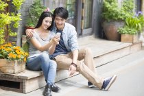 Chinesisches Paar ruht sich aus und nutzt Smartphone — Stockfoto