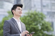 Китайський бізнесмен, стоячи з смартфон — стокове фото