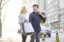 Pareja china madura con bolsas de compras en la ciudad - foto de stock