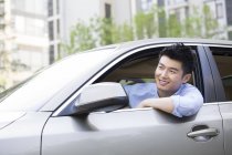 Uomo cinese guida auto e sorridente — Foto stock