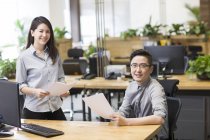 Chinese colleagues posing with papers in office — Stock Photo
