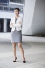 Femme d'affaires chinoise debout devant un immeuble de bureaux avec les bras croisés — Photo de stock