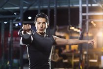 Chinese man training with kettlebell in crossfit gym — Stock Photo