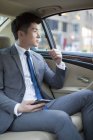 Homme d'affaires chinois assis sur le siège arrière de la voiture — Photo de stock