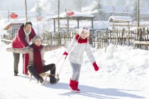 Chinesische Mädchen ziehen Schlitten mit Großeltern im Schnee — Stockfoto