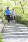 Chinese mature couple running on stairs in park — Stock Photo