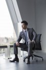 Homme d'affaires chinois regardant par la fenêtre dans le bureau — Photo de stock