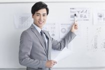 Chinesischer Geschäftsmann zeigt Strategie auf Whiteboard im Büro — Stockfoto