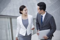 Chinese business people walking on stairs and talking — Stock Photo