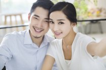 Chinese couple sitting cheek to cheek in cafe — Stock Photo