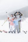 Chinese family posing at ski resort with ski poles — Stock Photo