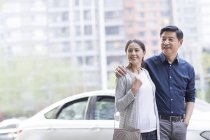 Зрелая китайская пара, стоящая перед машиной — стоковое фото