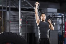 Chinese man training with kettlebells in crossfit gym — Stock Photo