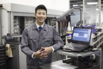Chinese auto mechanic standing with laptop — Stock Photo